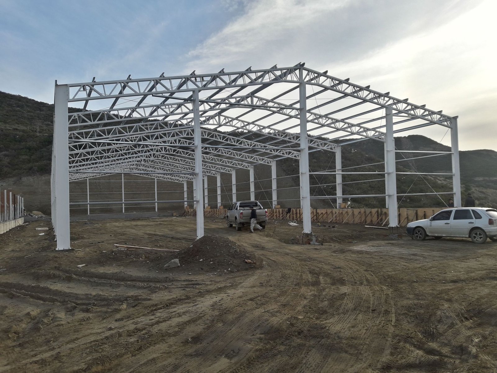 Estructura metálica de una nave industrial construida por Lgm contra un cielo nublado