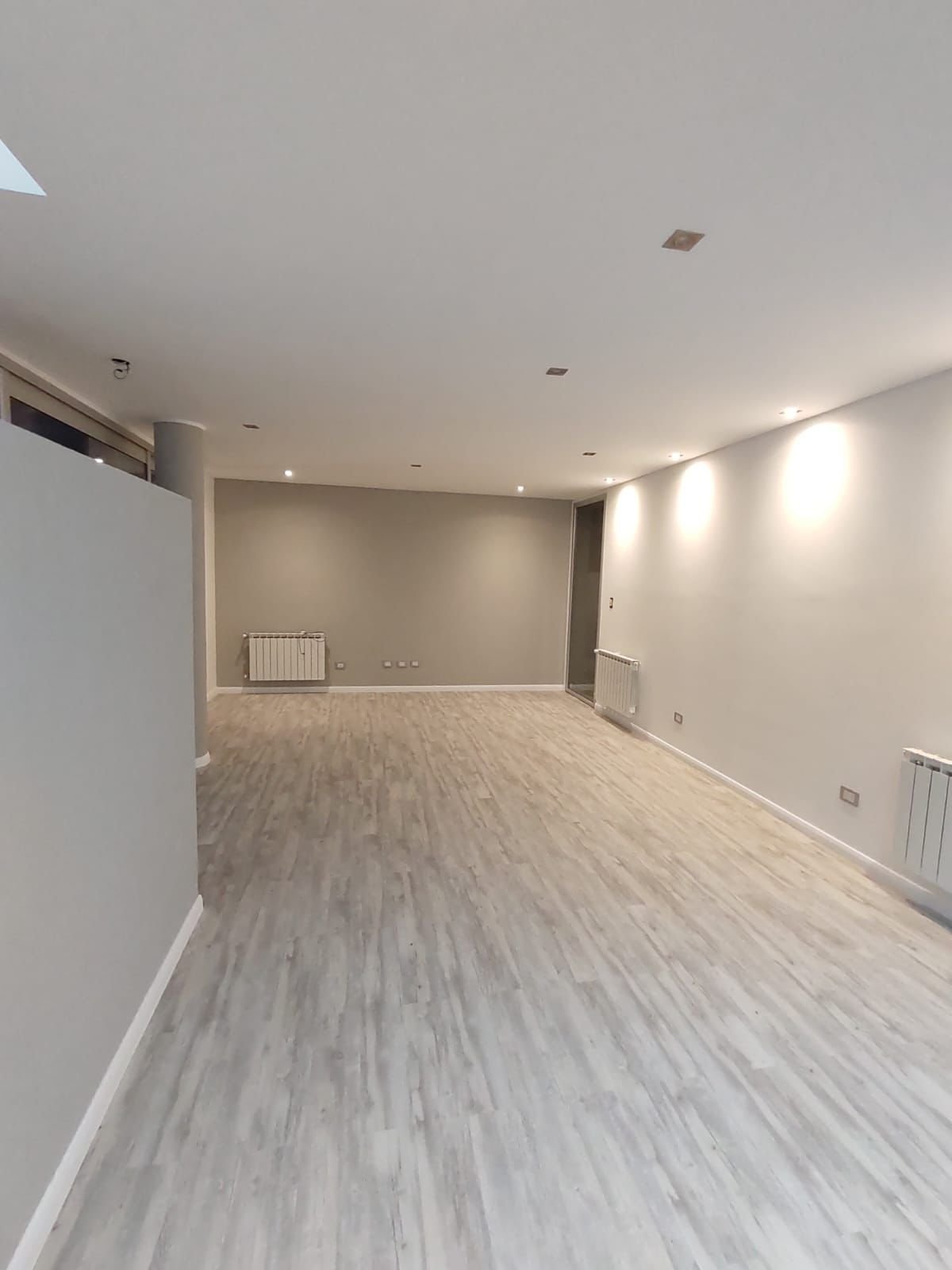 Living de una vivienda terminada, con piso de madera y luz indirecta